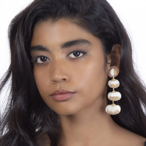 Model wearing Tiered shell earrings with gold accents